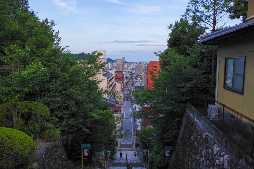 階段の上から見下ろす。遠くの山に松山城が見えた。